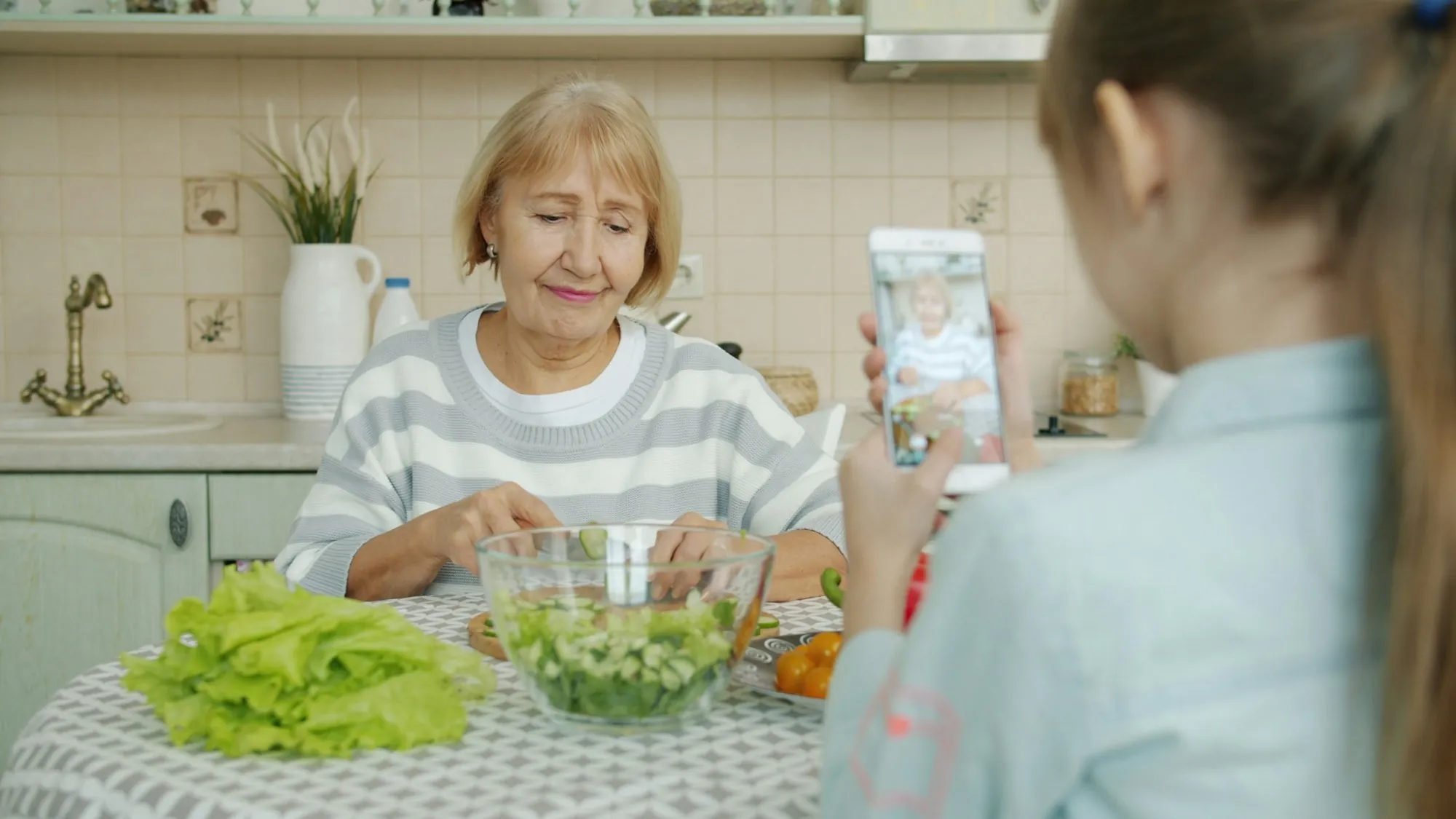 A grandmother and a younger woman preparing food together in a bright kitchen